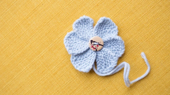 10. Alusta uue kroonlehe kudumist. Koo kokku kuus kroonlehte. Viimasel kroonlehel koo kõik s-d maha. Kasuta lõngaotsasid ja seo kroonlehed kokku. Allesjäänud lõnga abil saad õie sobivale kohale kinnitada. Õie südamikuks võid õmmelda nööbi või pärli.